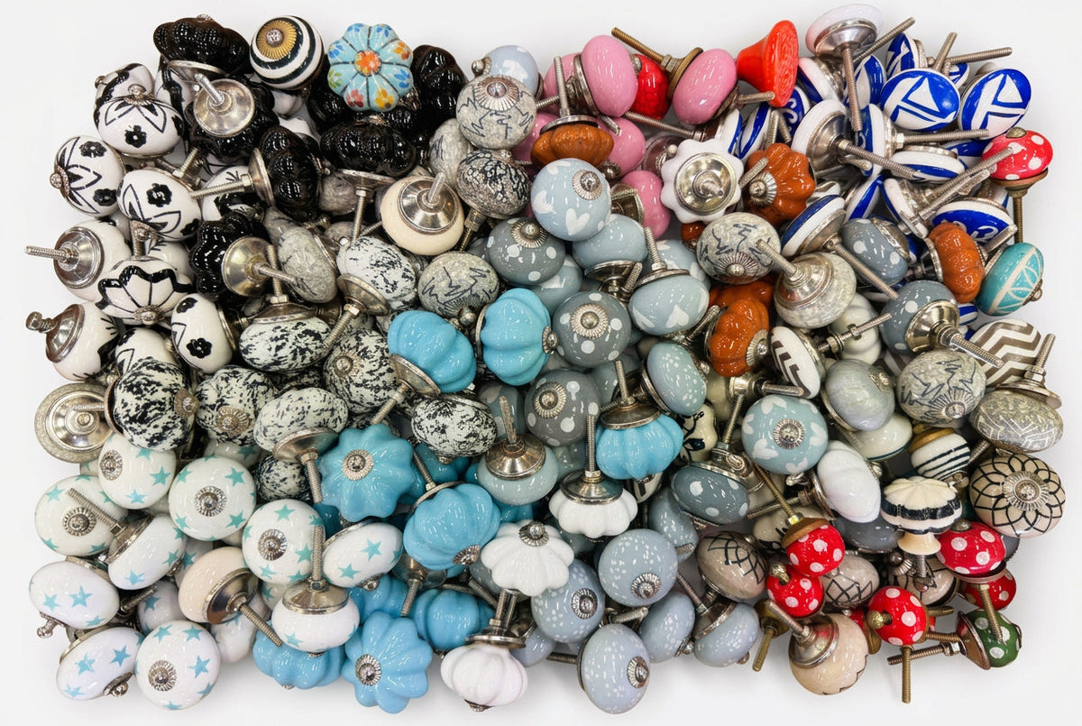 A large assortment of decorative ceramic cabinet knobs in various colors, patterns, and shapes, neatly arranged inside a wooden drawer or box.