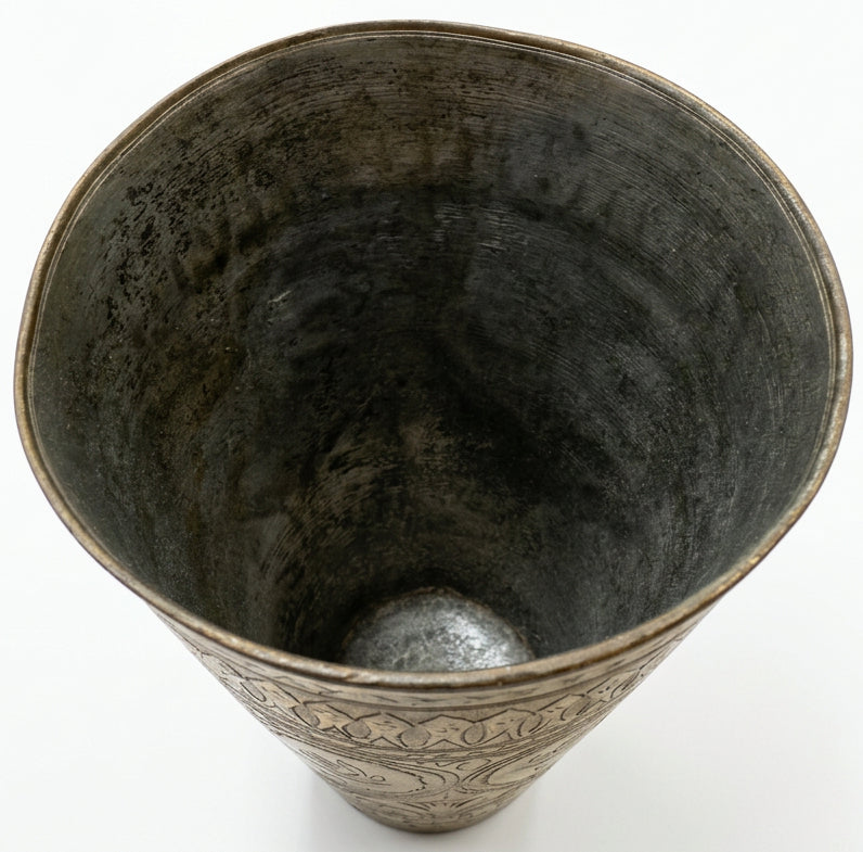 A large, rustic metal bucket or tub with a textured, weathered silver-gray finish, shown from a top-down perspective on a dark wooden table.