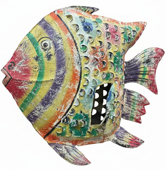 A large, hand-painted metal fish sculpture with a vibrant rainbow pattern and textured shell details, displayed on a dark wooden table inside a home decor store.