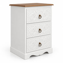 A three-drawer white bedside embossed floral patterns on the drawer fronts, a dark brown wooden top, and round metal ring pulls, shown against a plain off-white wall.
