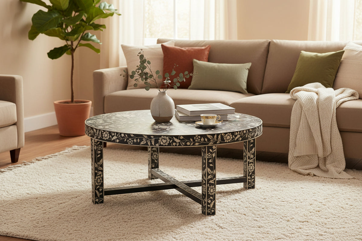 A round, handcrafted inlay coffee table with a floral pattern around the edge and a black metal frame.